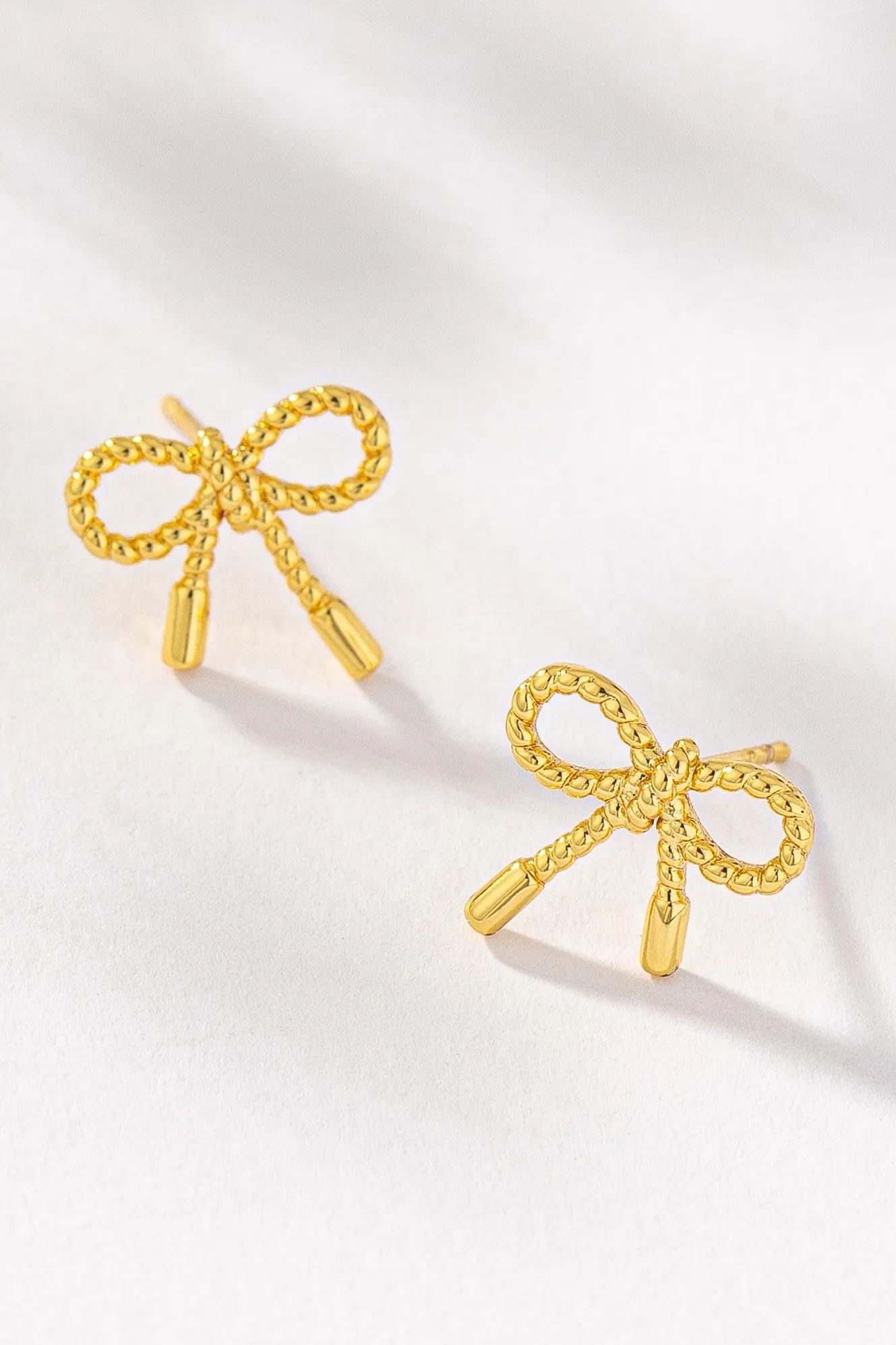 Small textured brass bow stud earrings