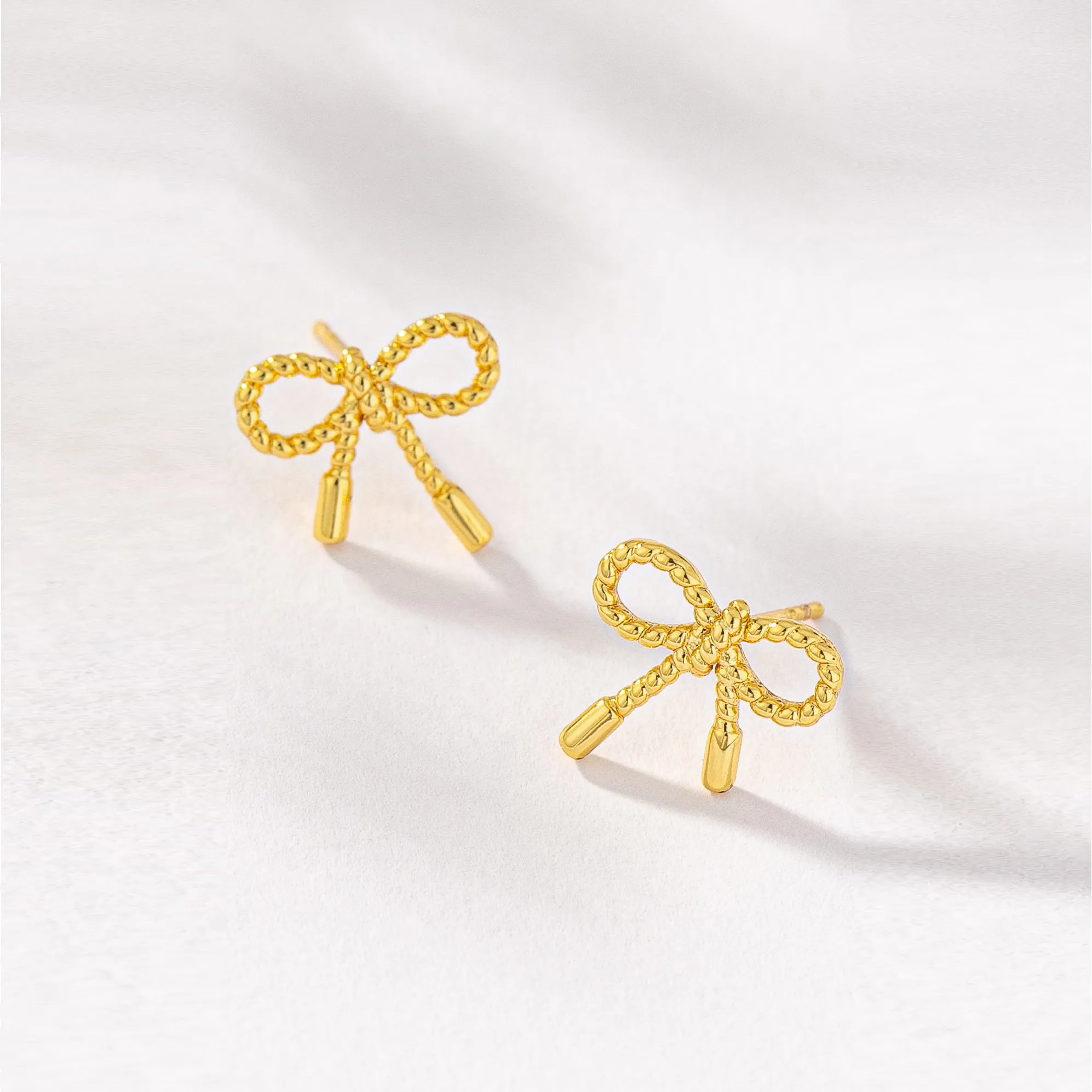 Small textured brass bow stud earrings